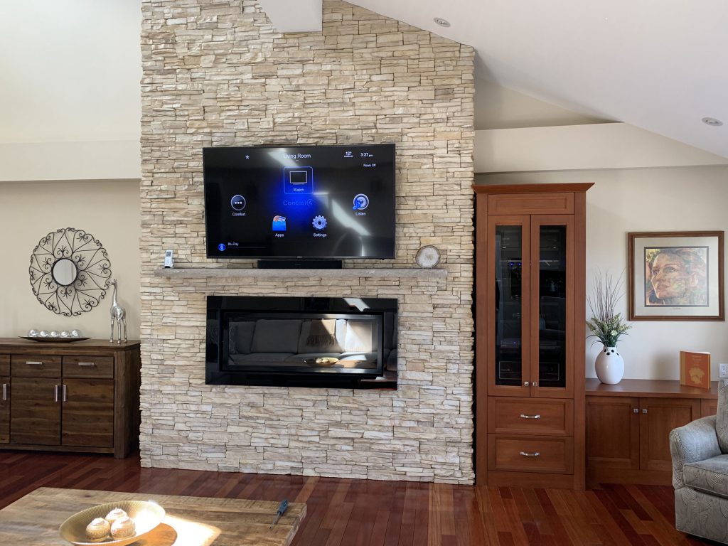 TV mounted on stone wall with Sonos Beam soundbar below and whole home audio video distribution