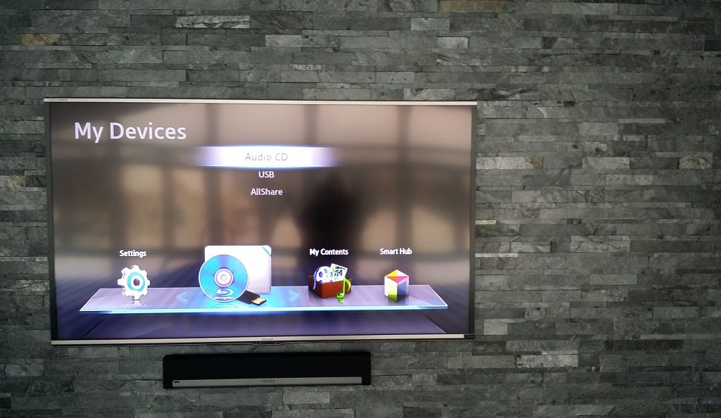 TV mounted on stone wall with centralized audio video control
